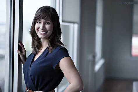 A smiling worker standing by a window in a workplace